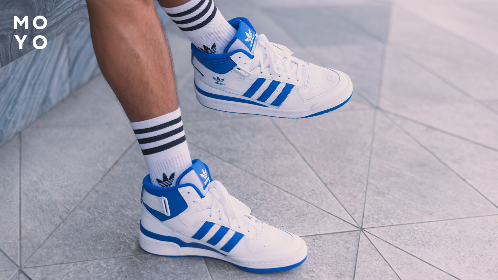 Біло-блакитні кросівки на ногах хлопця