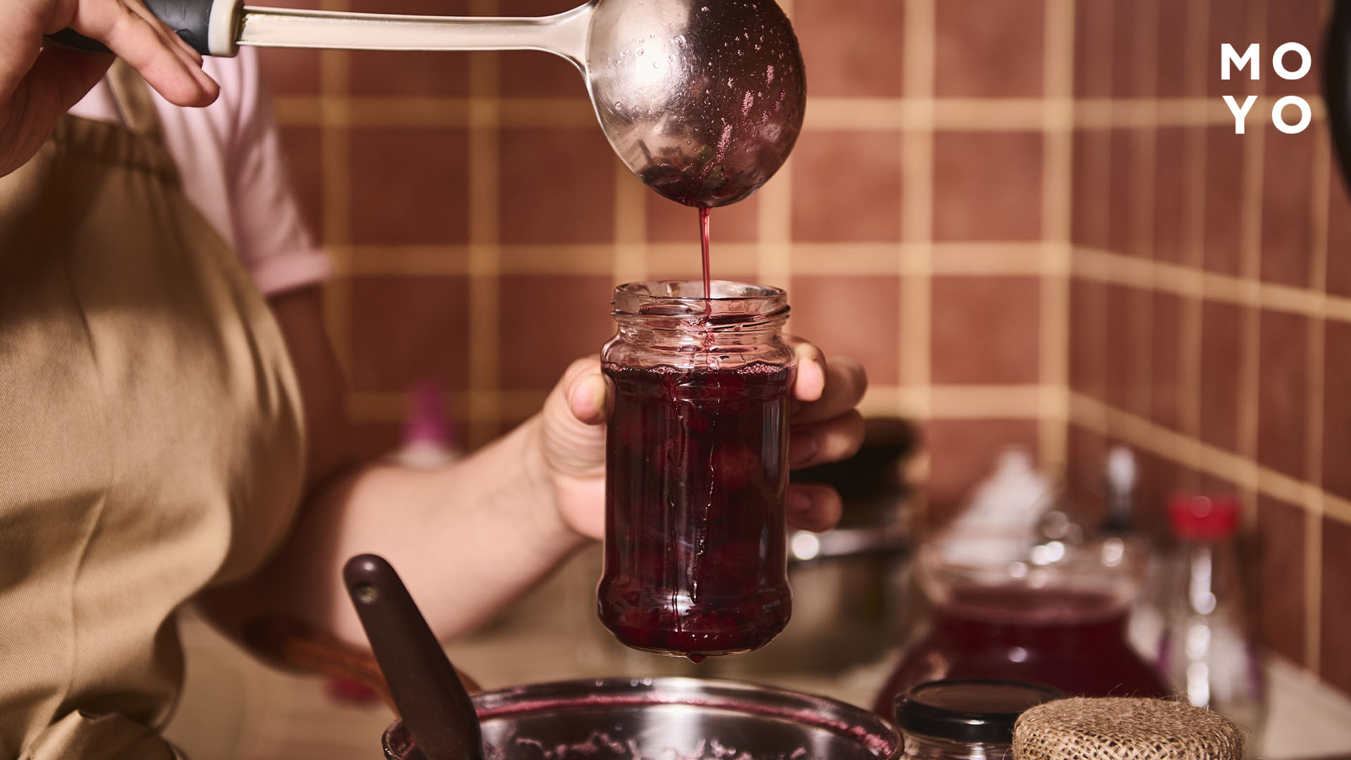 господиня наливає джем у банку