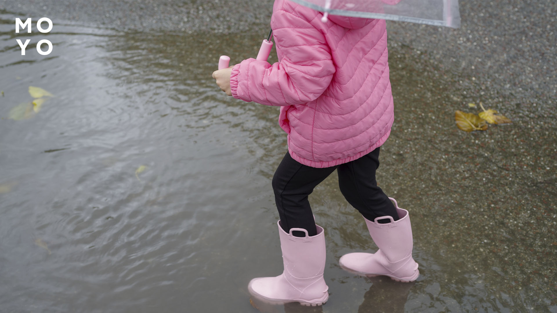 дівчинка в чобітках гуляє по калюжах