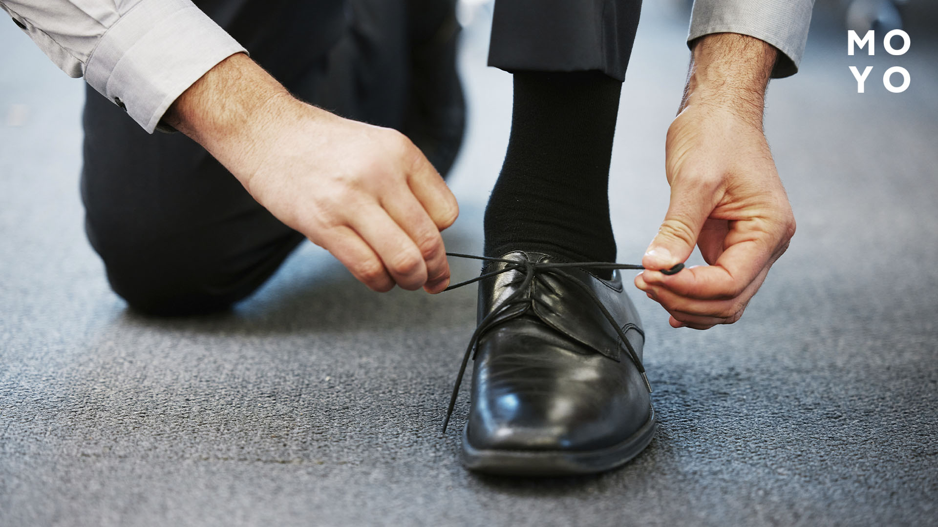 чоловік зав’язує чорні туфлі